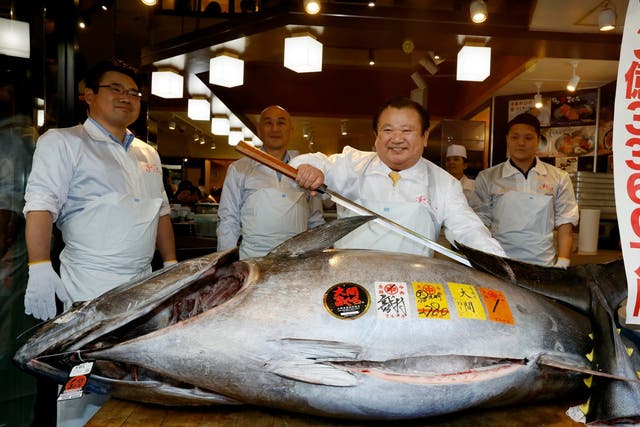 Kiyoshi Kimura (centre) stands over the huge bluefin tuna he bought for £2.5m