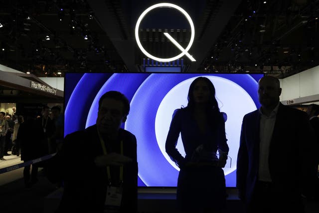 Attendees stand in front of a QLED TV at the Samsung booth during CES International in Las Vegas