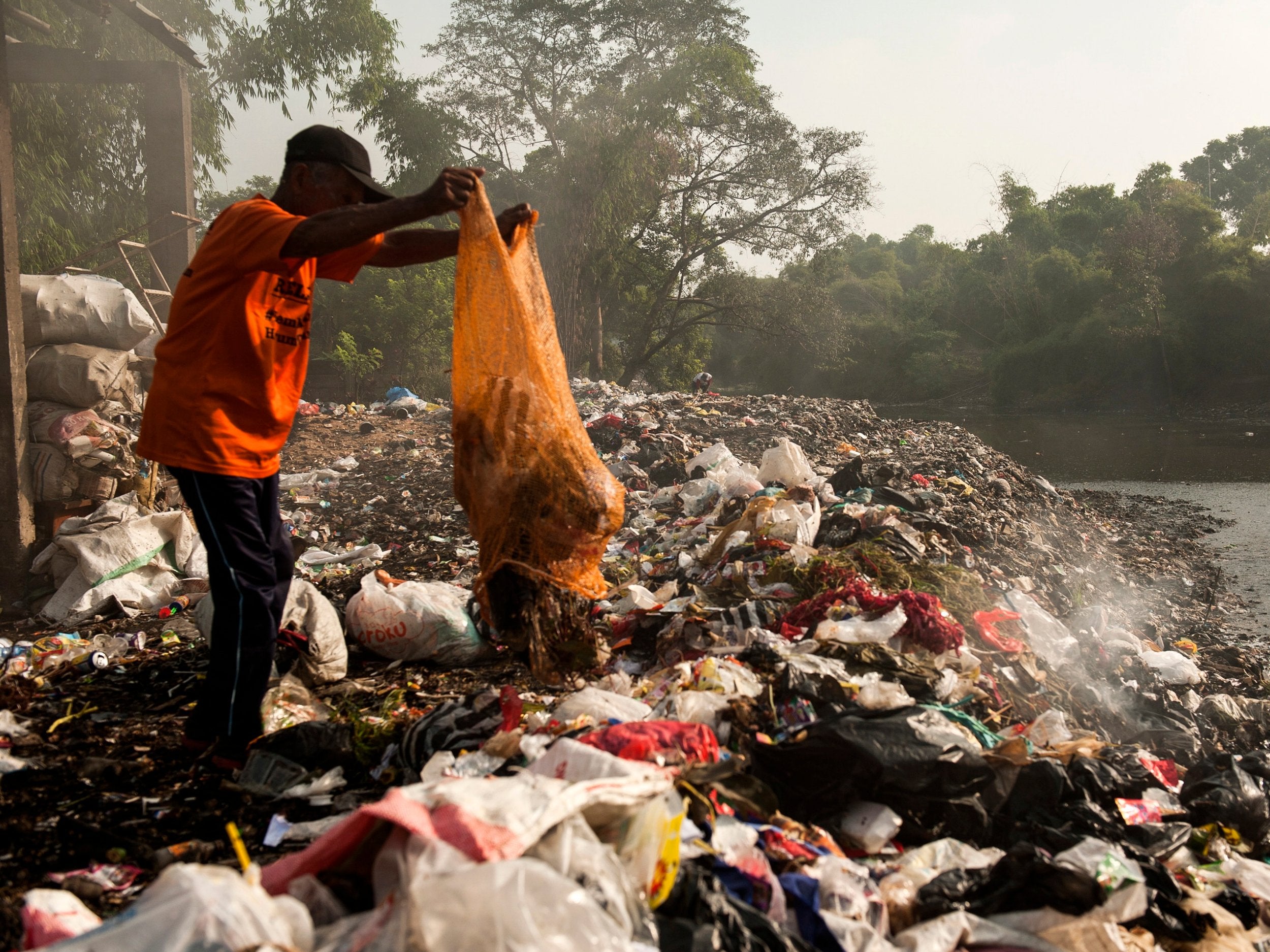 An man sorts useable plastic waste on a polluted bank of the Citarum River in Bandung, Indonesia. According to reports, Citarum is one of the most polluted rivers in the world, with tons of plastic waste and wastewater