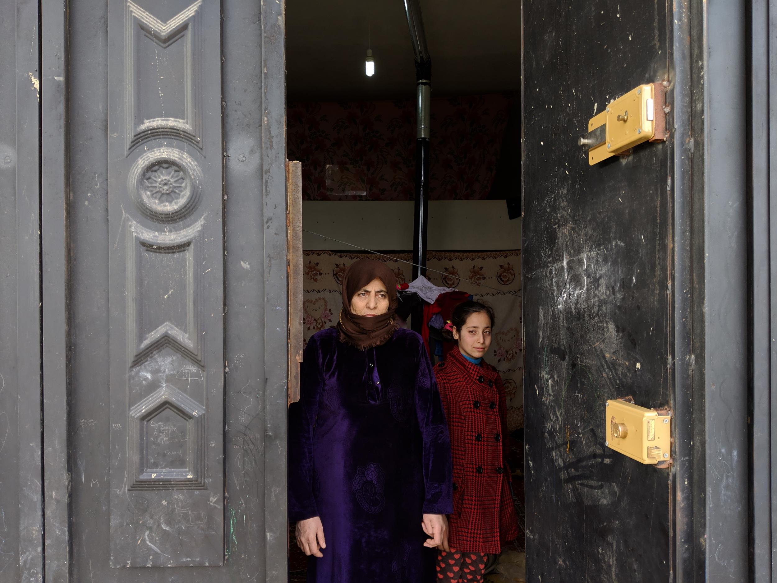 Syrian refugees Jose Ahmad al-Jessi, a mother of eight in her 50s, and her daughter Raghad stand in the doorway of a shop warehouse where they fled to when their tent flooded on Tuesday