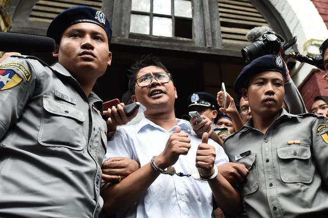 Wa Lone is escorted by police after being sentenced by a court to jail in Yangon in September