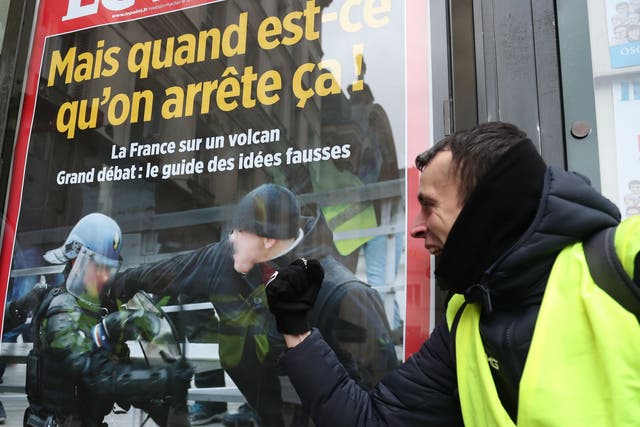 A protester poses next to the front page of a magazine depicting French boxer Christophe Dettinger who punched two French gendarmes last week, as he takes part in an anti-government demonstration called by the Yellow Vest "Gilets Jaunes" movement in Paris, on January 12, 2019. - France braced for a fresh round of "yellow vest" protests on January 12, 2019 across the country with the authorities vowing zero tolerance for violence after weekly scenes of rioting and vandalism in Paris and other cities over the past two months. (Photo by Zakaria ABDELKAFI / AFP)ZAKARIA ABDELKAFI/AFP/Getty Images