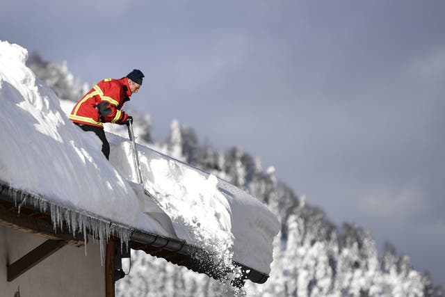 A fireman clears a roof following heavy snowfall in Kruen, Germany