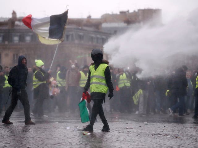 Yellow vest protesters are sprayed with water near the Arc de Triomphe in Paris