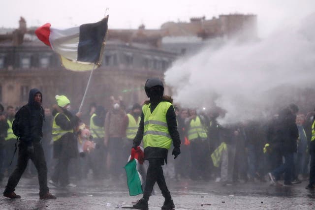 Yellow vest protesters are sprayed with water near the Arc de Triomphe in Paris