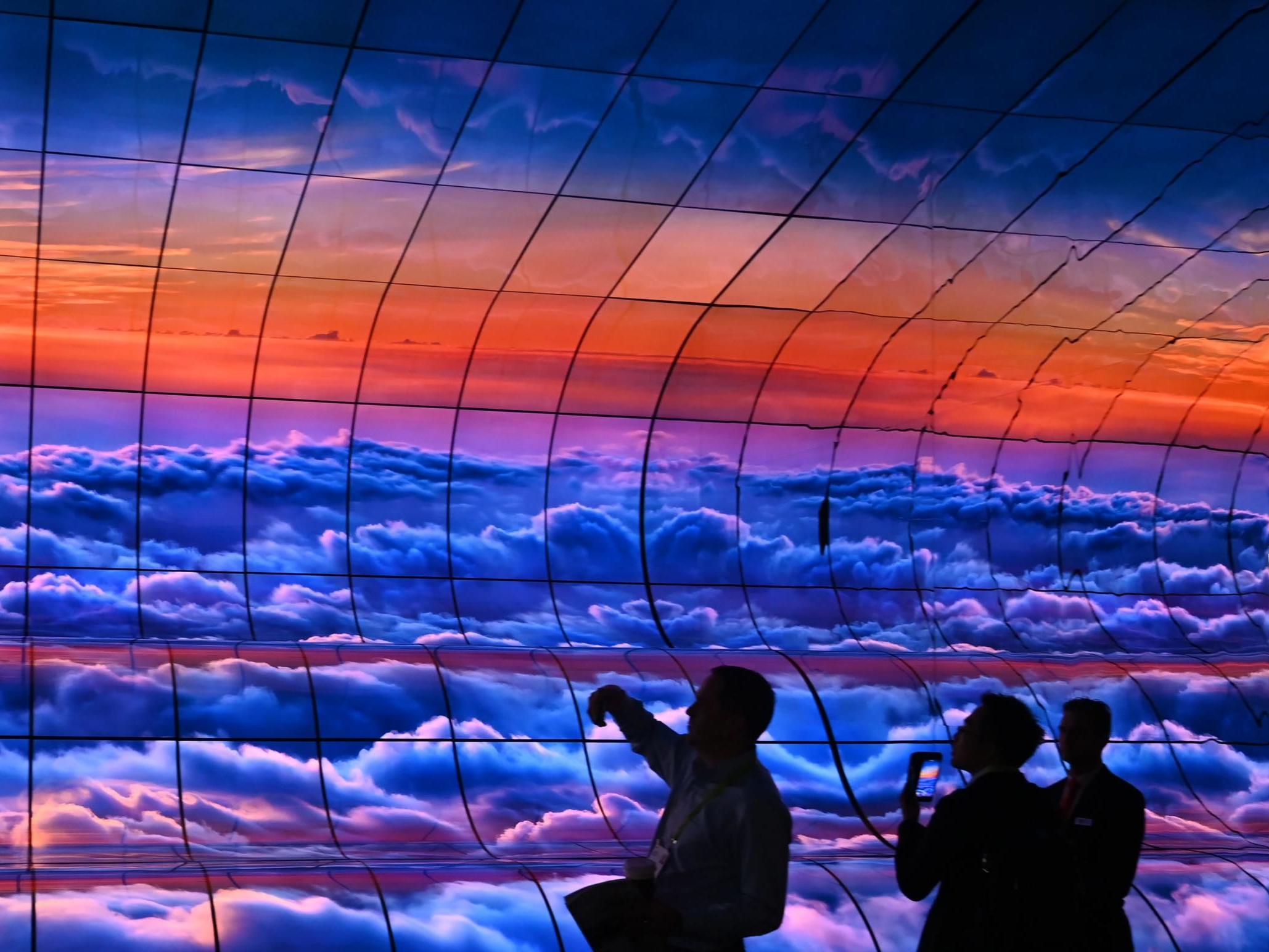 Attendees photograph the "Massive Curve of Nature" display of 250 curved LG OLED televisions on the last day of CES 2019, 11 January 2019 at the Las Vegas Convention Center in Las Vegas, Nevada