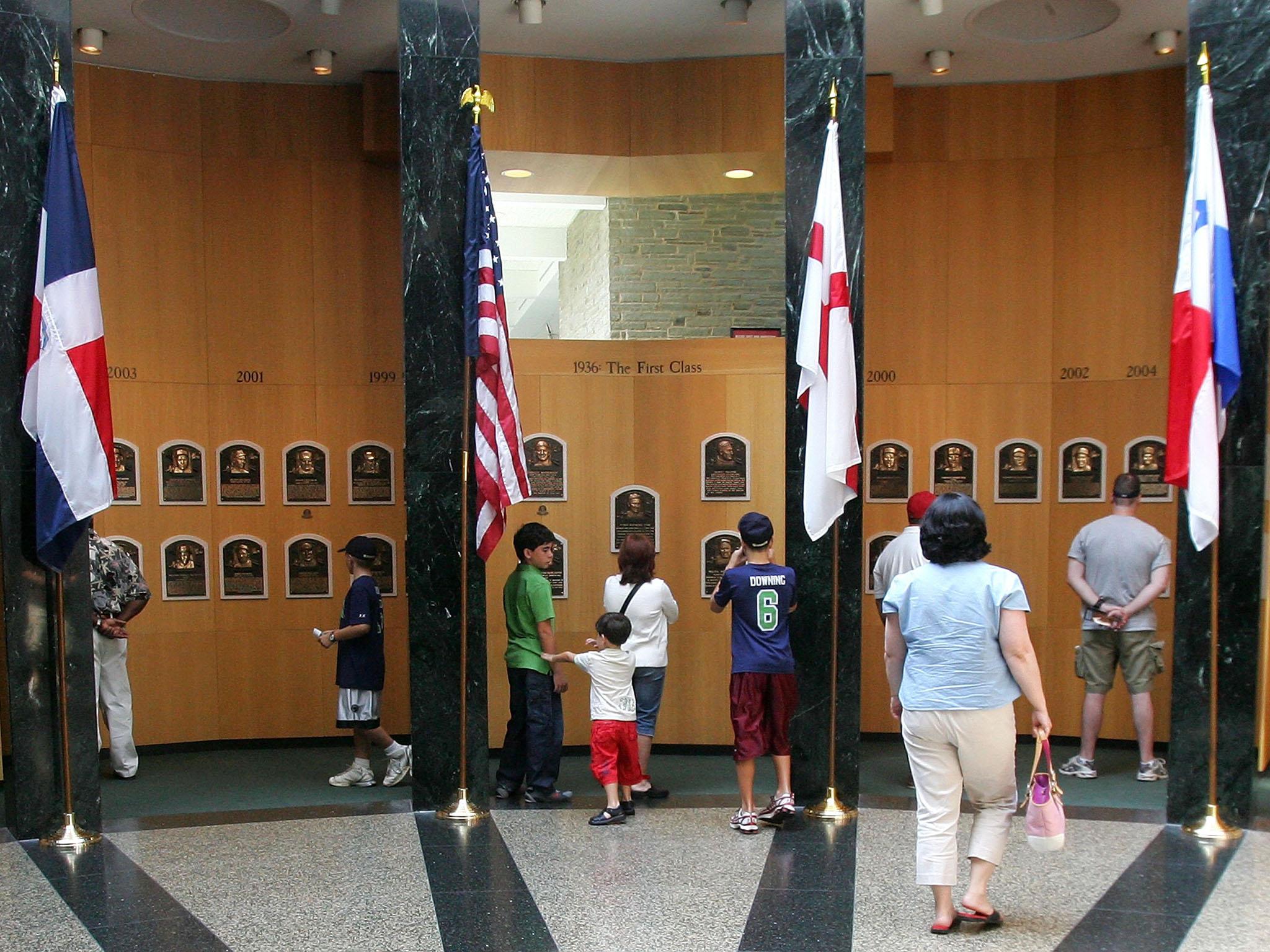 Fans look at the plaques of players inducted into the National Baseball Hall of Fame and Museum in New York