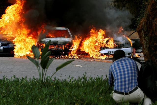 Cars are seen burning at the scene of explosions and gunshots in Nairobi, Kenya, on Tuesday