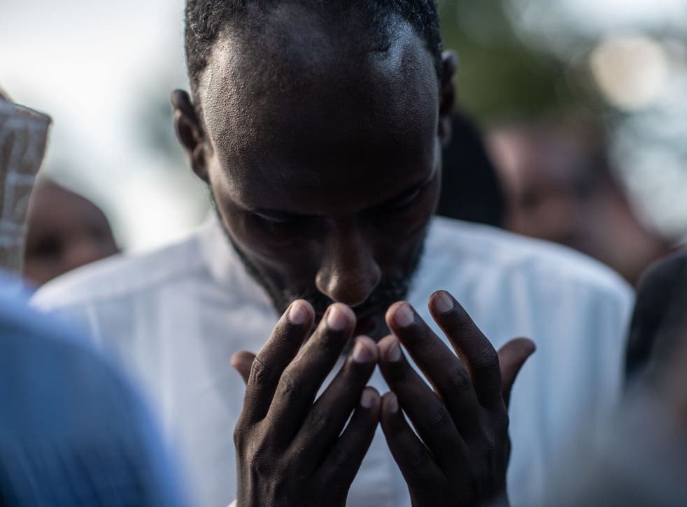 A man prays at the burial for two men killed in Tuesday’s attack
