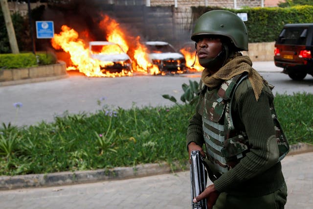 A police officer runs past burning cars at the scene where explosions and gunshots were heard at the Dusit hotel compound in Nairobi