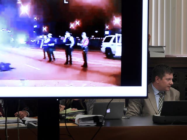 Next to an image of Laquan McDonald's body lying in the street, Chicago police Officer Jason Van Dyke listens in during the trial for the shooting death of Laquan McDonald at the Leighton Criminal Court Building in Chicago, Illinois September 18, 2