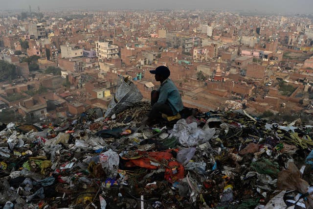 A young Indian ragpicker looks over the city after collecting usable material from a garbage dump at the Bhalswa landfill site in New Delhi