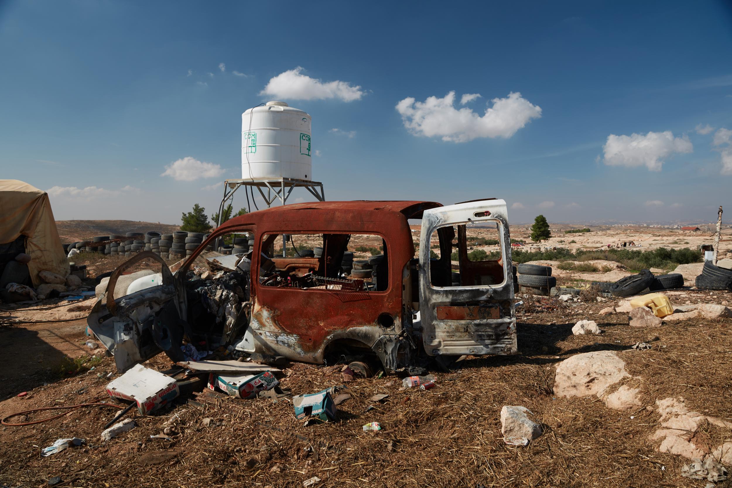 A van rusts in the sun in Susya, West Bank. The encampment’s water tower can be seen behind the truck