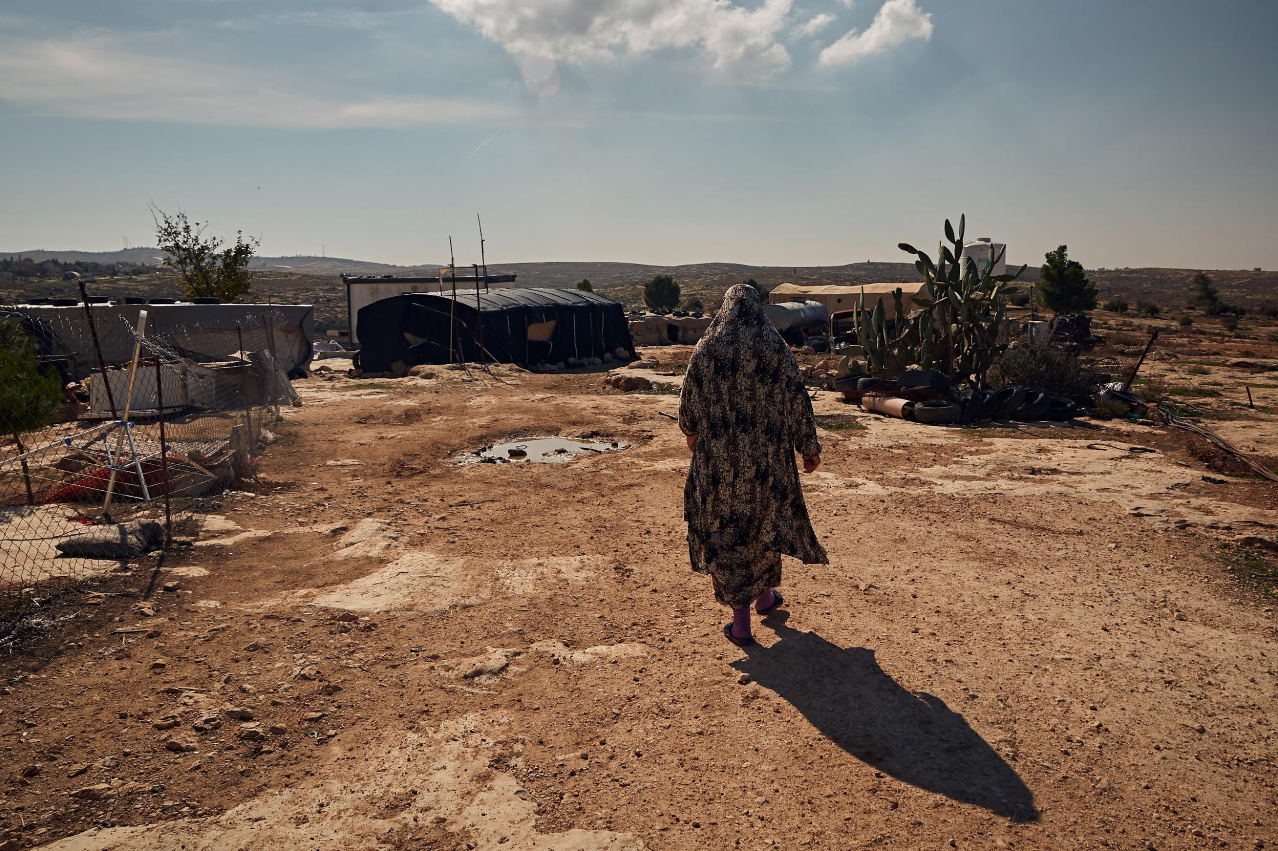 A Bedouin woman walks through the Susya encampment in the South Hebron Hills, West Bank