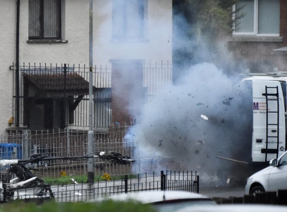 Debris shoots out of a suspect van as police carry out a controlled explosion