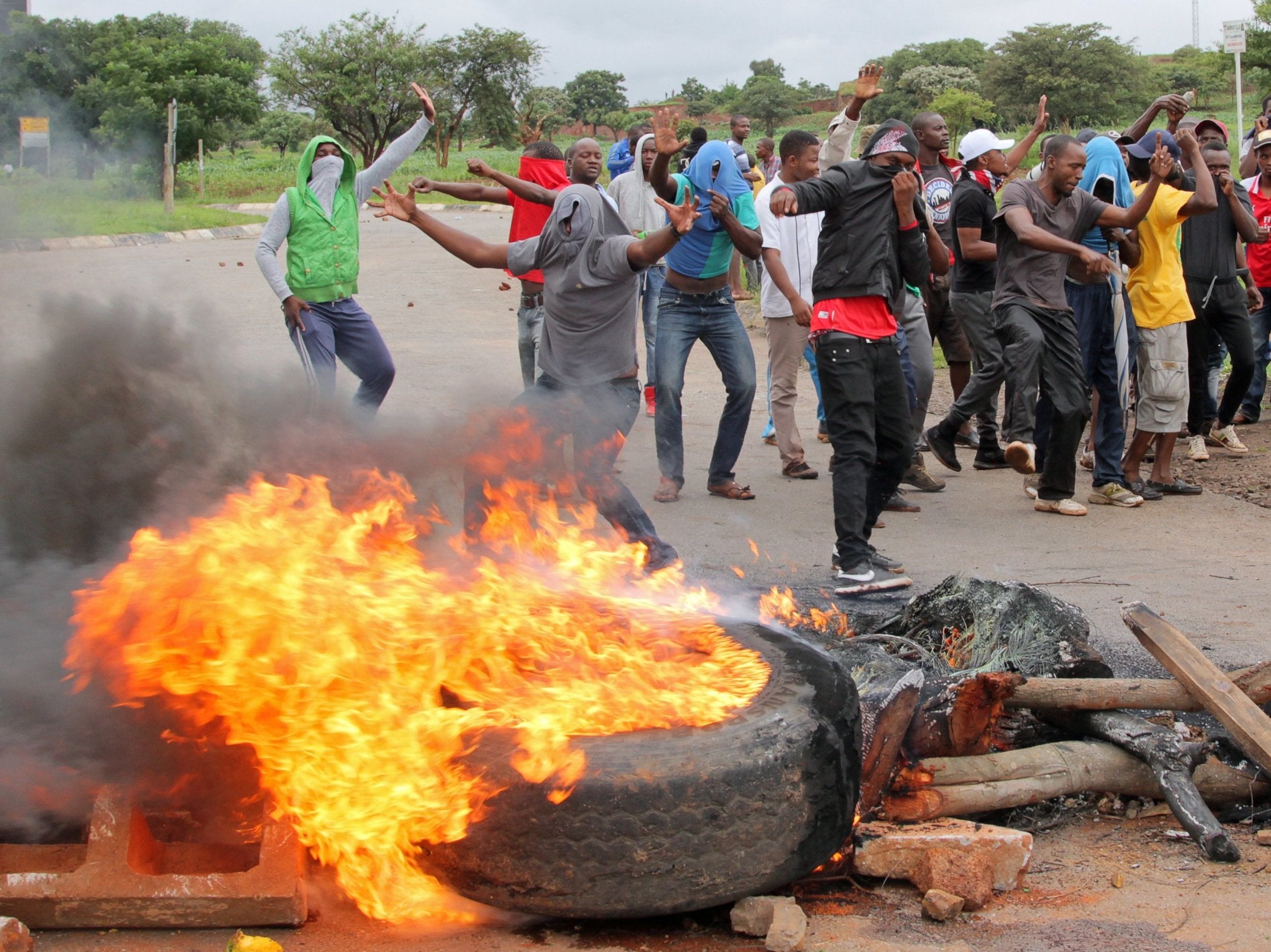 Demonstrators behind a burning barricade on a road leading to Harare