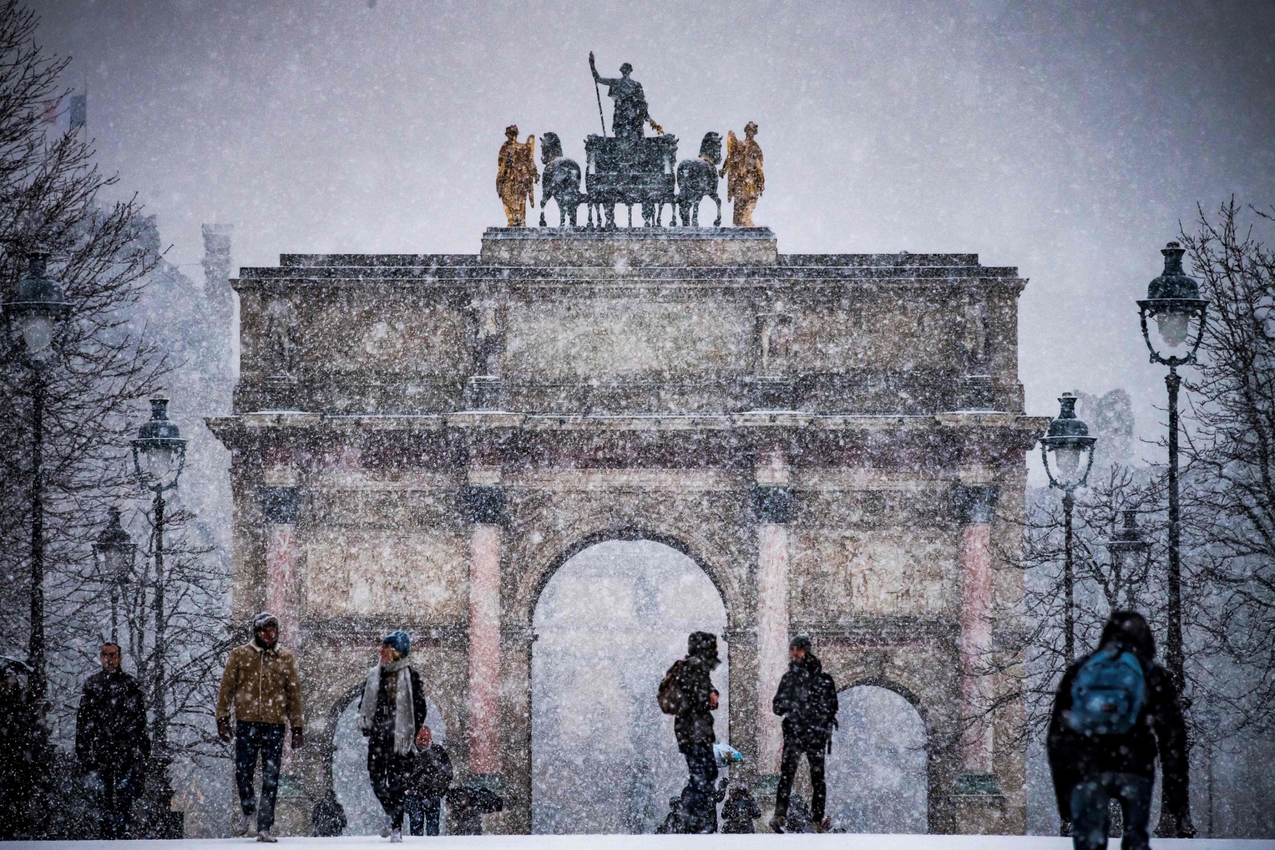 Tourists are pictured in the Tuileries garden as snow falls over Paris