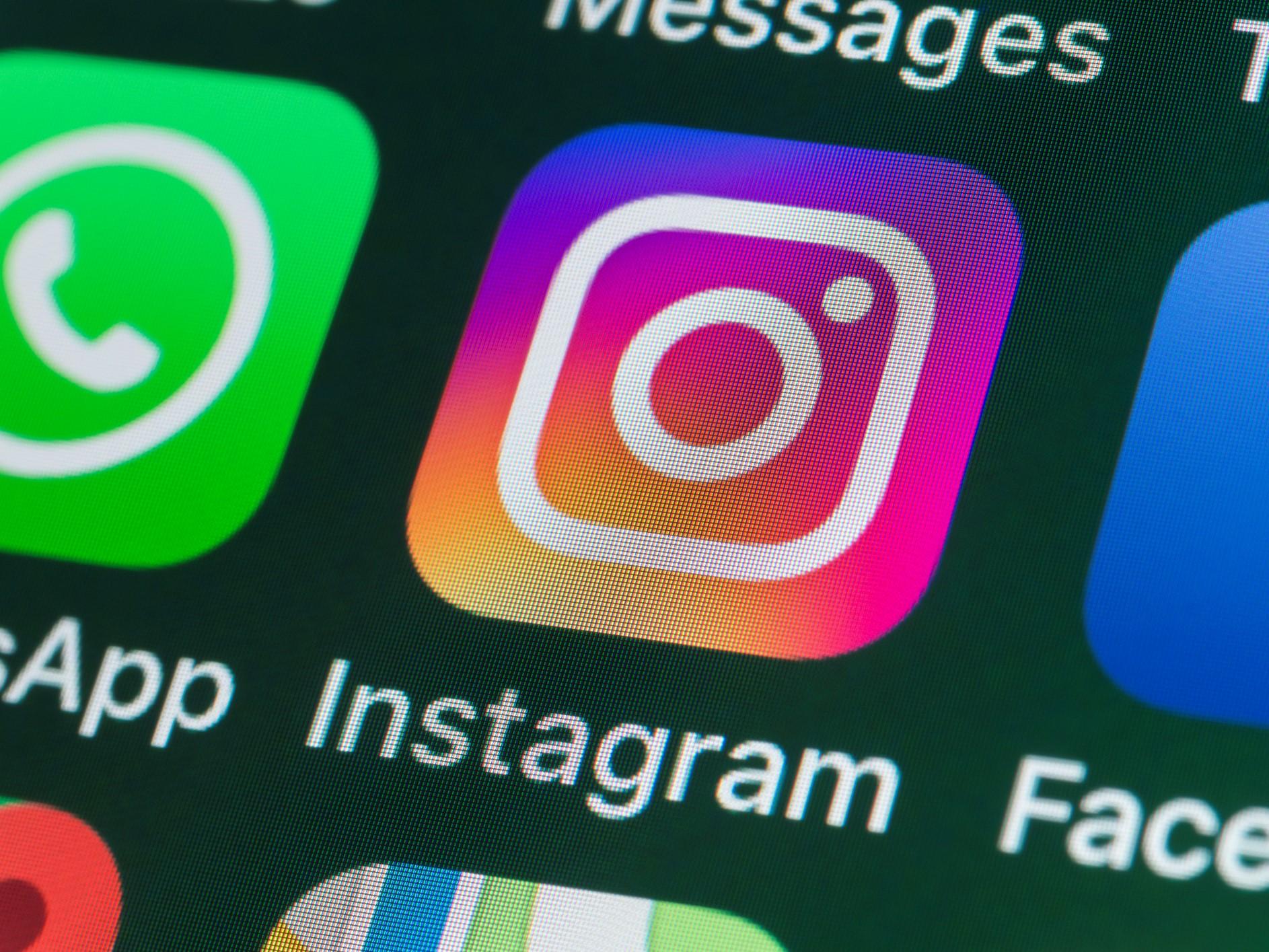 The app for Instagram, surrounded by WhatsApp and Facebook on the screen of an iPhone