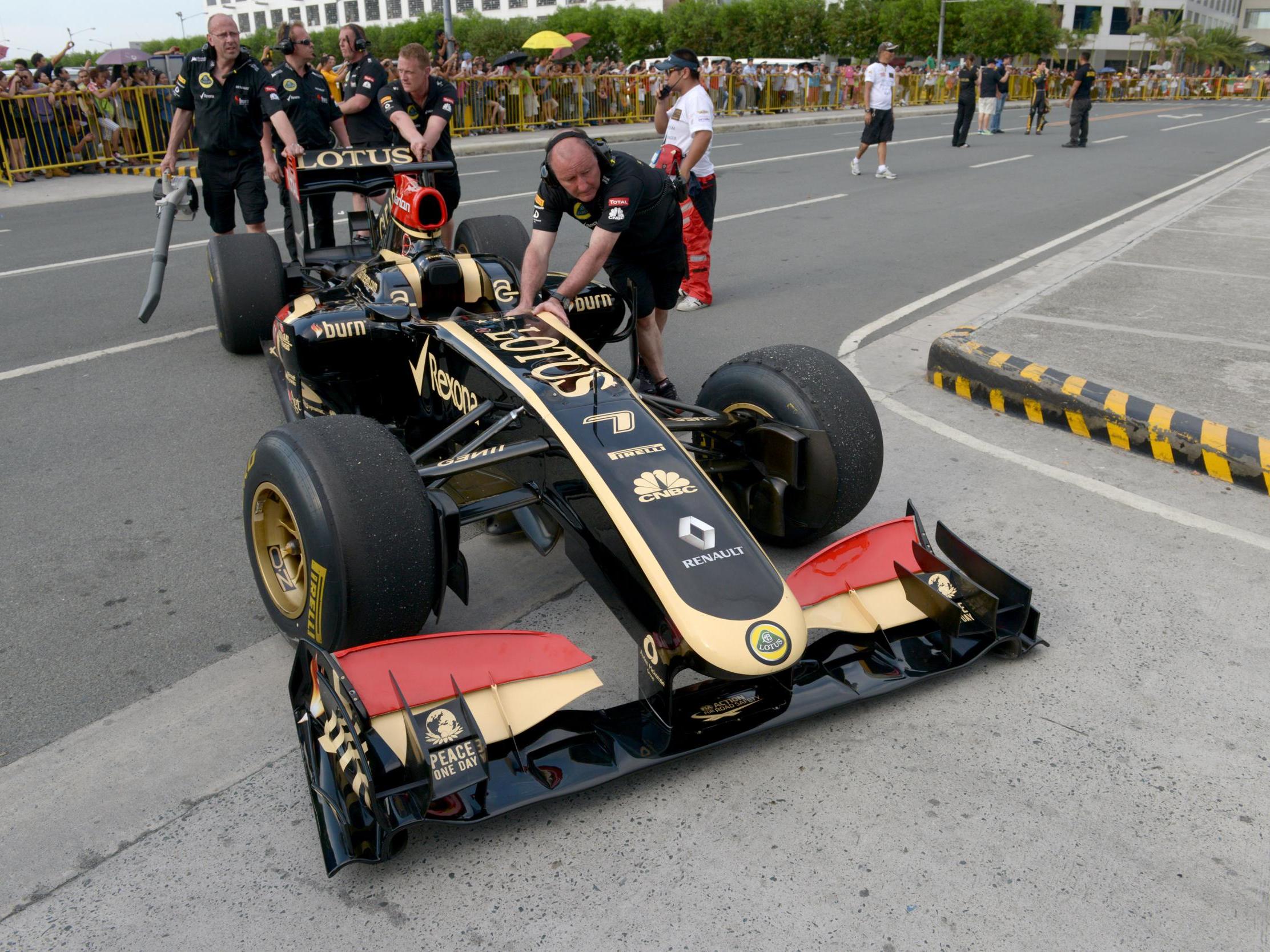 Mechanics push a Lotus Formula One car back to the pits after Filipino-Swiss racer Marlon Stockinger performed for fans during an event at the Manila Speed Show in Manila on May 4, 2013