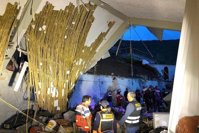 Police officers and firefighters stand by a collapsed area of the Alhambra hotel in Abancay, Peru