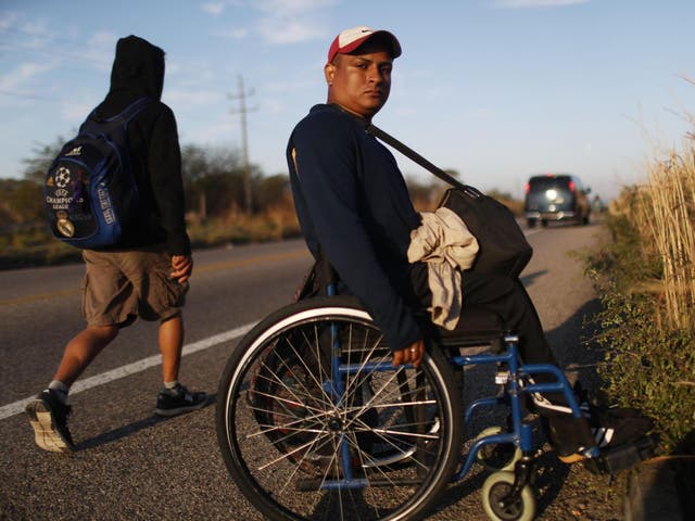 Kevin, who became paralysed by a stray bullet in Honduras, poses along the highway as he continues towards the US with fellow Central American migrant caravan members, on 22 January 2019, near Santo Domingo Zanatepec, Mexico.