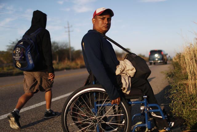 Kevin, who became paralysed by a stray bullet in Honduras, poses along the highway as he continues towards the US with fellow Central American migrant caravan members, on 22 January 2019, near Santo Domingo Zanatepec, Mexico.