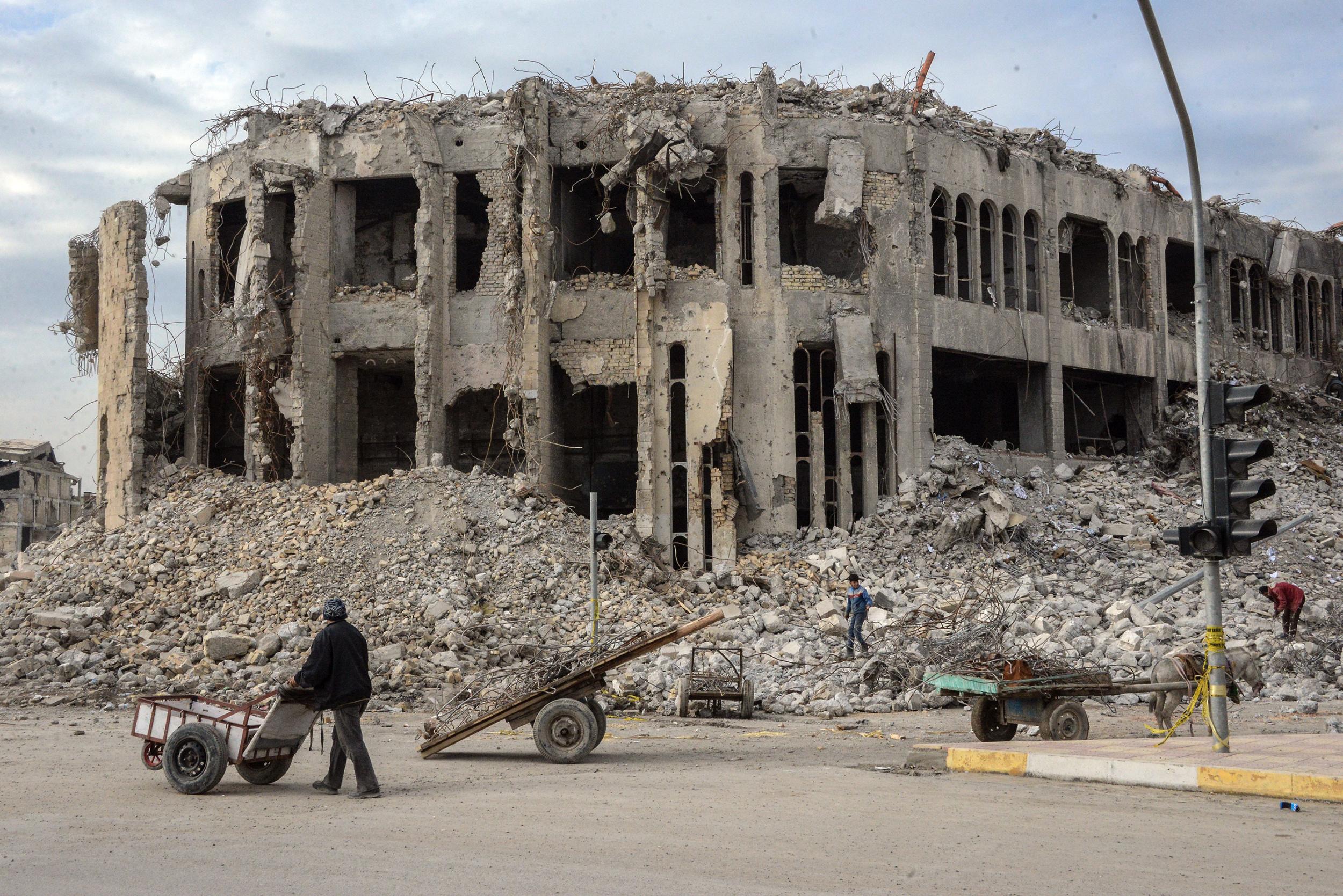 An Iraqi pushes his cart past a building once used by Isis to throw men accused of being gay to their deaths (AFP/Getty)