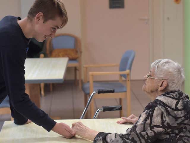 A teennager with psychological difficulties (L) holds the hand of a woman with Alzheimer's disease in a retirement home on 18 October 2016 in Saint Quirin, eastern France.
