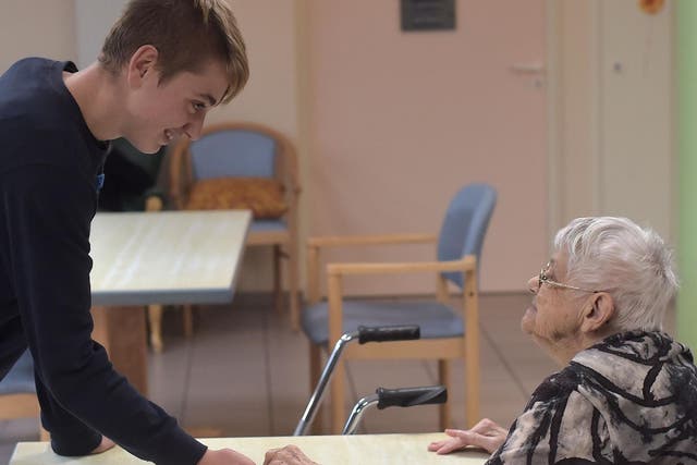A teennager with psychological difficulties (L) holds the hand of a woman with Alzheimer's disease in a retirement home on 18 October 2016 in Saint Quirin, eastern France.