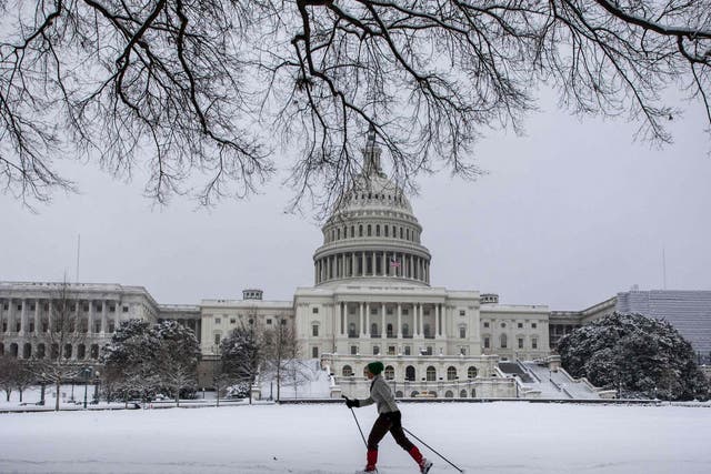 A woman cross country skis in front of the US Capitol as snow continues to fall in Washington, DC