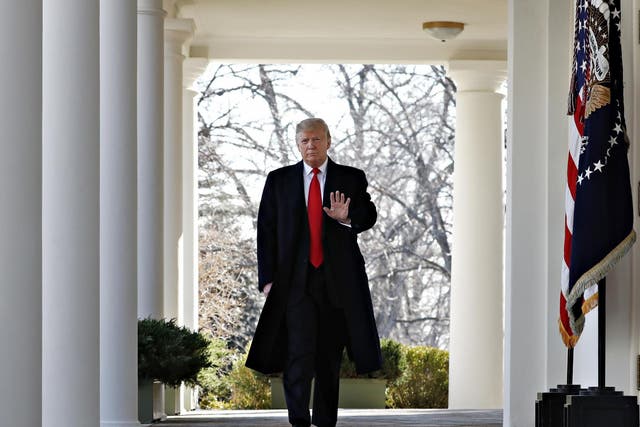 President Donald Trump waves as he walks through the Colonnade from the Oval Office of the White House