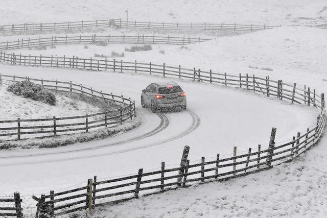 A car traverses a snow-covered road on Mam Tor near Castleton in central England