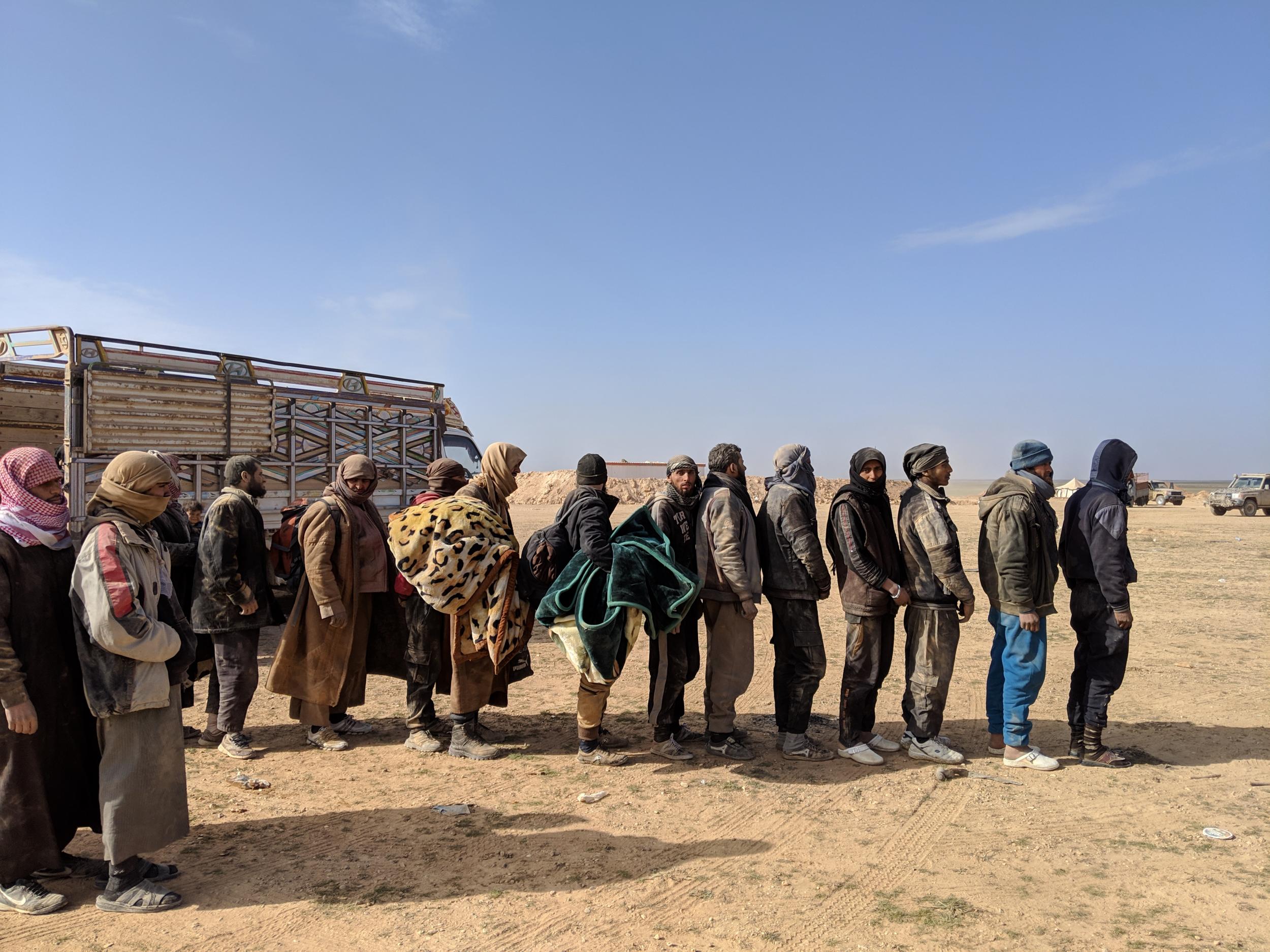 Men who fled the last Isis-held area of Syria line up to be questioned by US and Kurdish officials