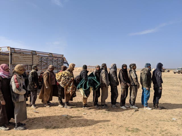 Men who fled the last Isis-held area of Syria line up to be questioned by American and Kurdish intelligence officials