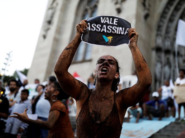 An activist covered in mud, holds a sign reading "VALE SA, killer" during a protest against the Brazilian mining company Vale SA, in front of the Se Cathedral in Sao Paulo, Brazil, 1 February 2019.