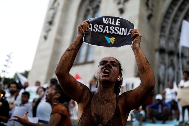 An activist covered in mud, holds a sign reading "VALE SA, killer" during a protest against the Brazilian mining company Vale SA, in front of the Se Cathedral in Sao Paulo, Brazil, 1 February 2019.