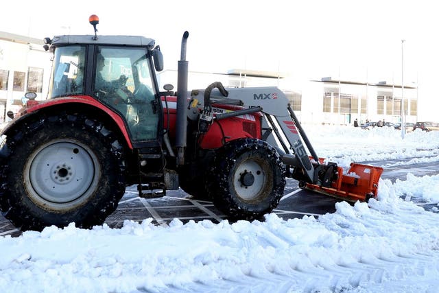 A tractor with a snow plough clears snow at a shopping park in Basingstoke