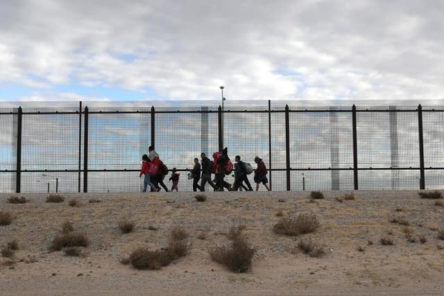 Central American immigrants walk along the US-Mexico border fence after crossing the Rio Grande from Mexico on 1 February 2019