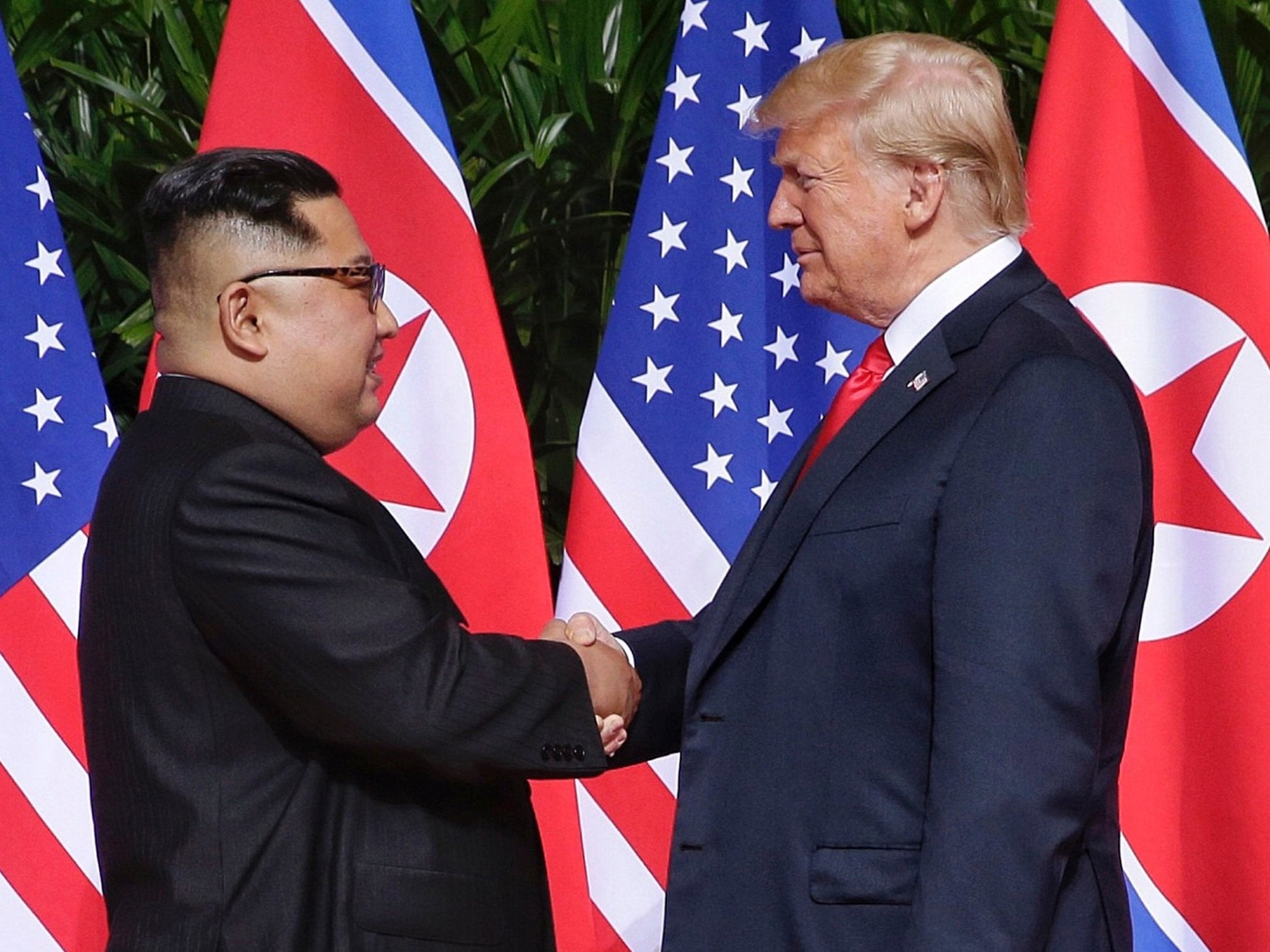 US President Donald J Trump (R) and North Korean leader Kim Jong-un (L) shake hands at the start of a historic summit in Singapore