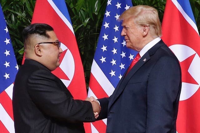 US President Donald J Trump (R) and North Korean leader Kim Jong-un (L) shake hands at the start of a historic summit in Singapore