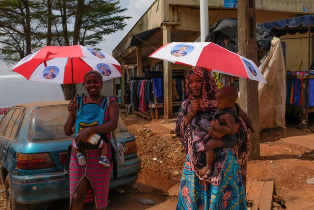 Women in Yaounde, Cameroon, carry umbrellas they received as campaign handouts featuring Paul Biya, president since 1982
