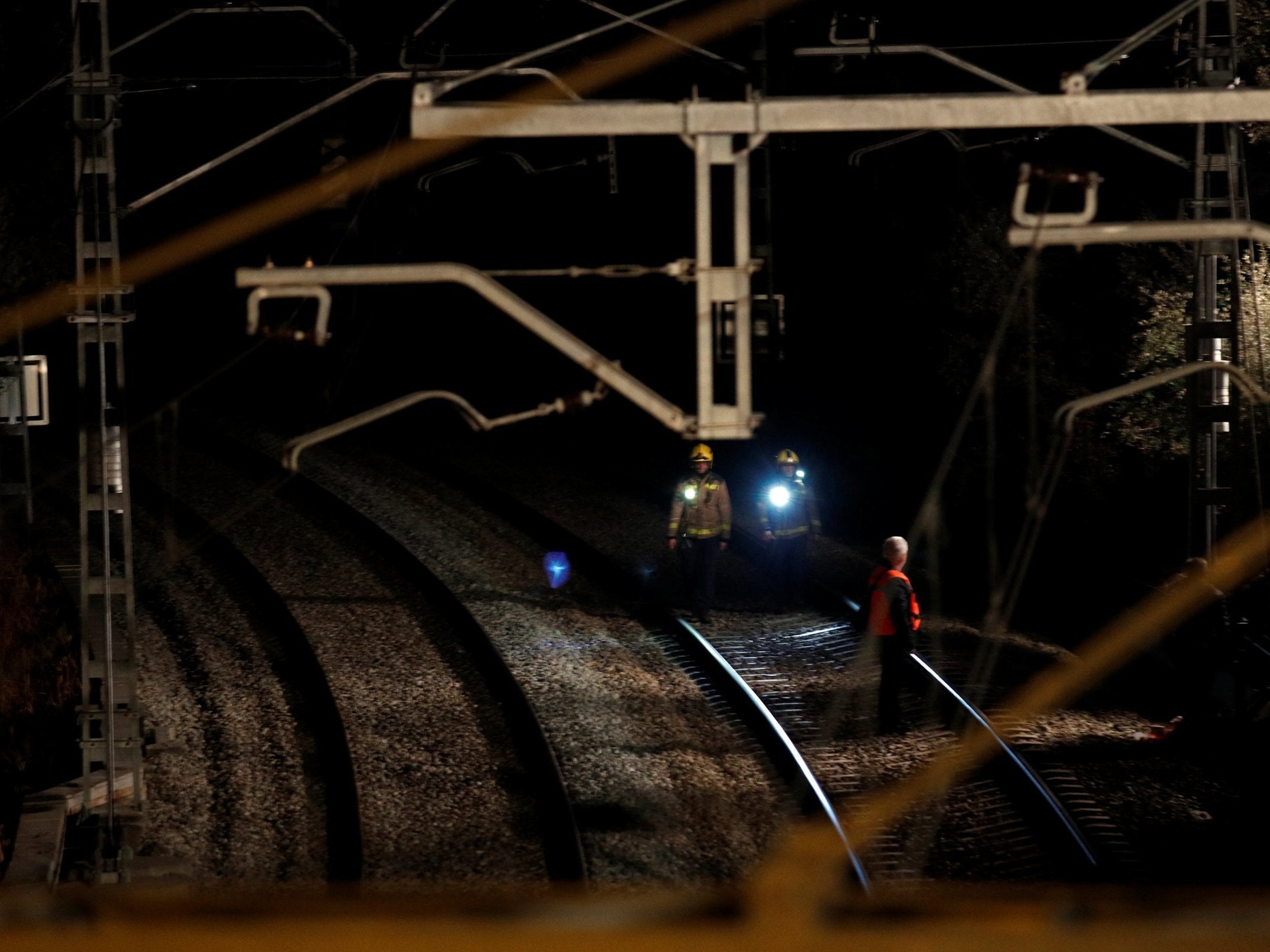 Security personnel inspect the railway after a train crash near Manresa