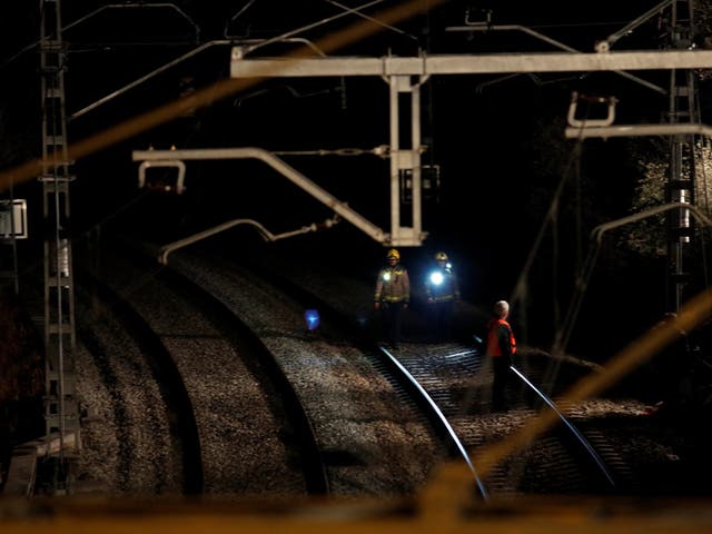 Security personnel inspect the railway after a train crash near Manresa