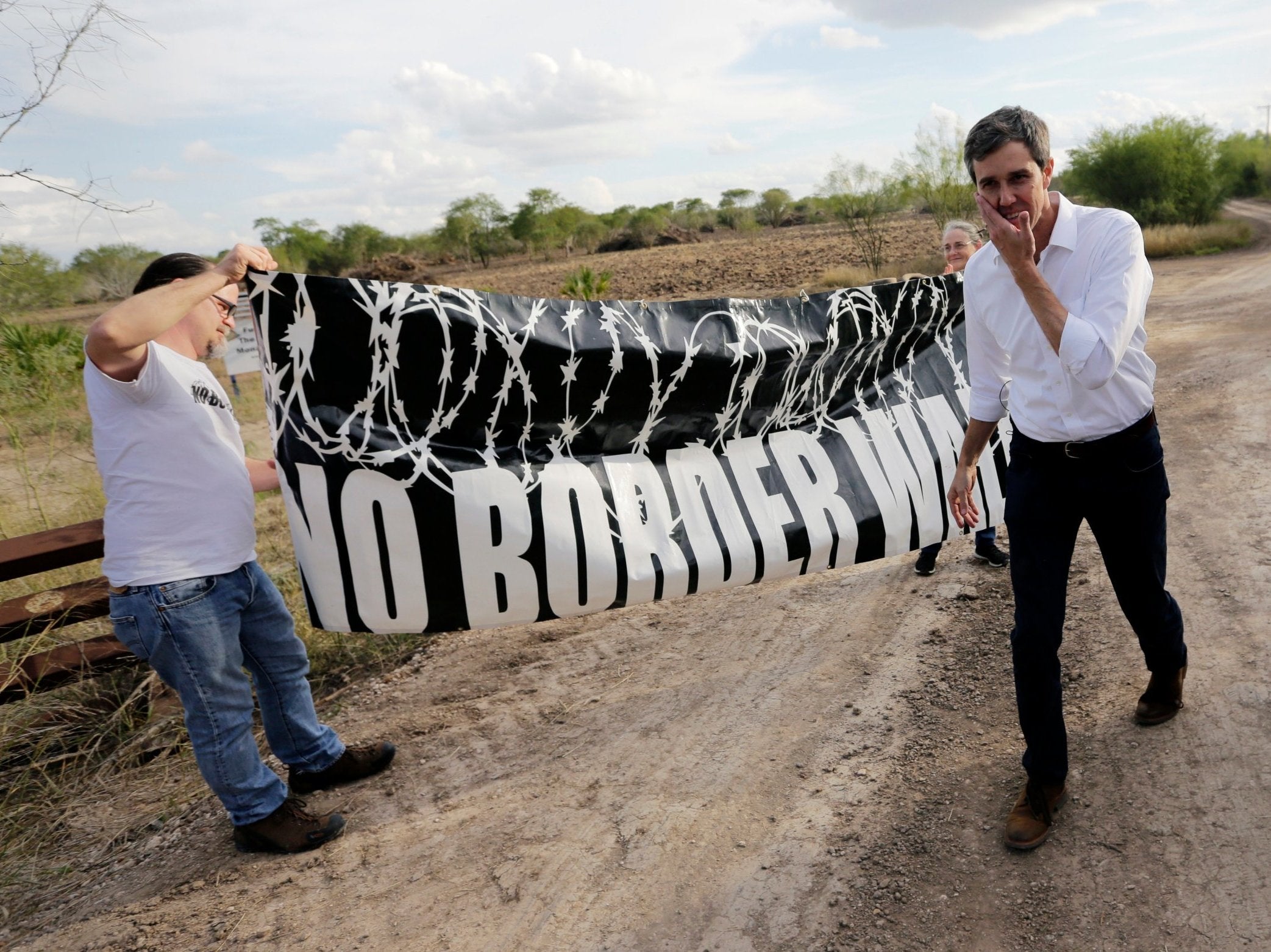 Texas Democratic Congressman Beto O'Rourke, right, passes a "No Border Wall" sign during a visit to the National Butterfly Center in Mission, Texas