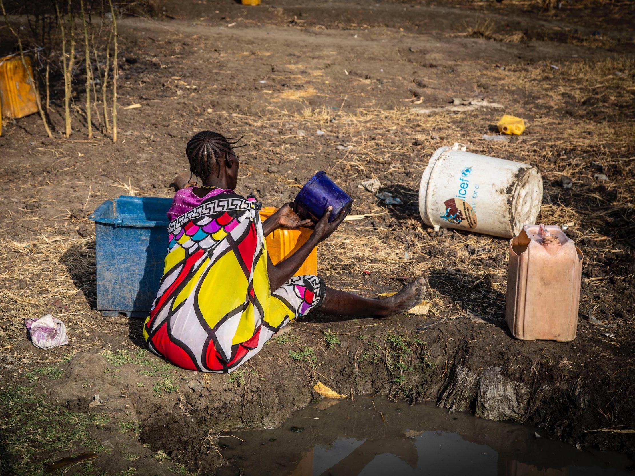 A woman from Pibor, South Sudan, has walked hours in punishing heat to the nearest water pump to fill a bucket of water