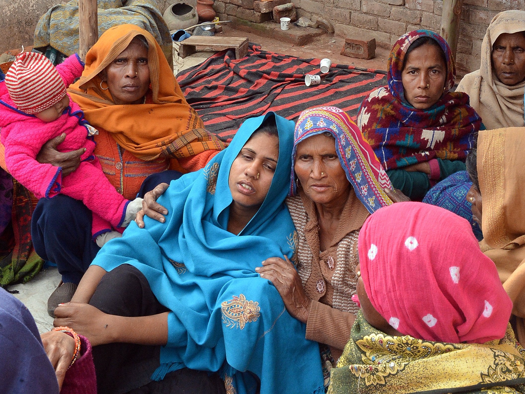 A woman is consoled after her husband's death from bootleg alcohol in Saharanpur, Uttar Pradesh, on Monday