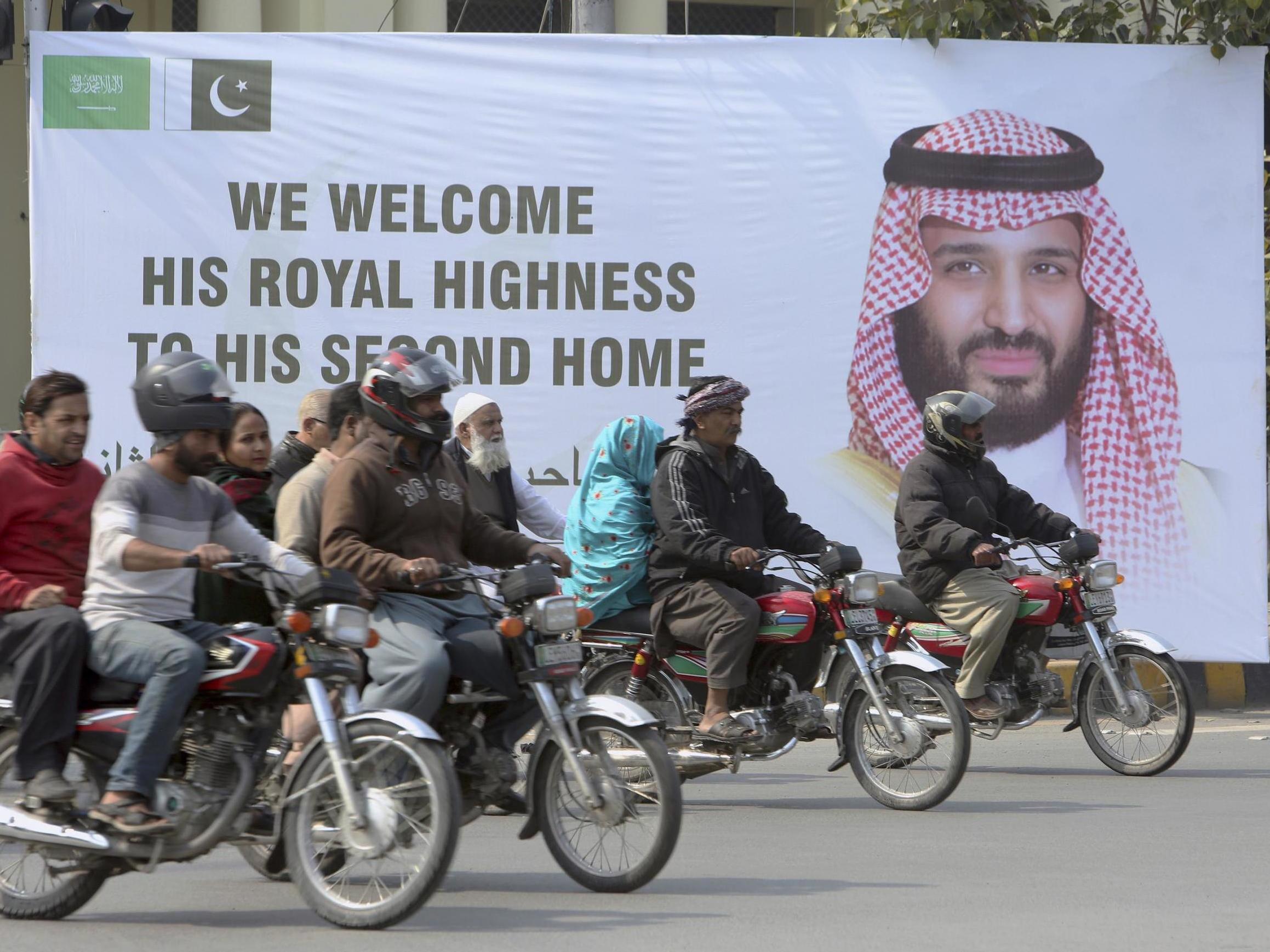 Pakistani motorcyclists pass by a banner welcoming Saudi Arabia's Crown Prince Mohammed bin Salman, displayed on the occasion of his visit in Lahore, Pakistan, on Saturday 16 February 2019.