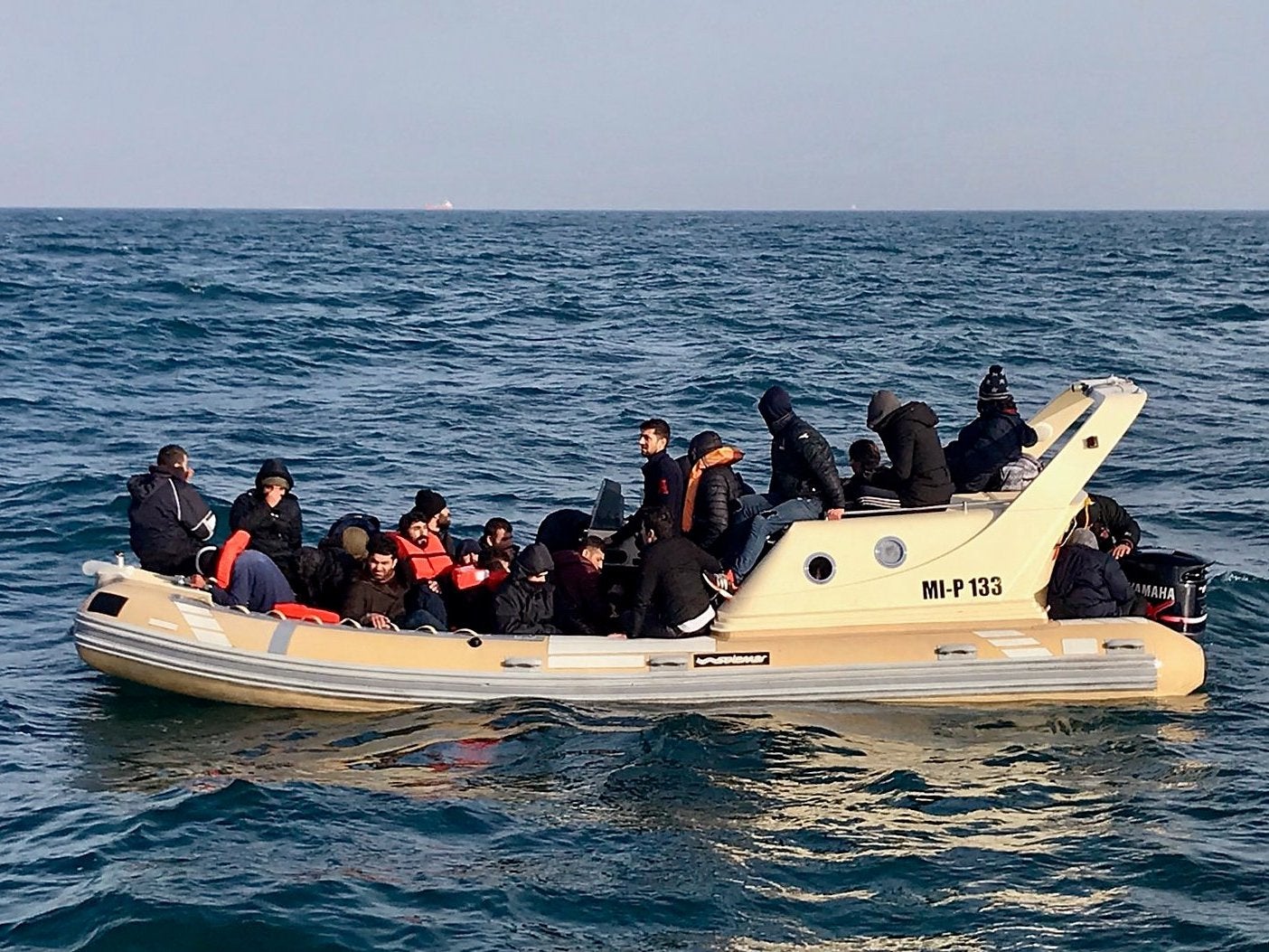 Rescuers help migrants on a semi-rigid boat trying make their way from France to the UK