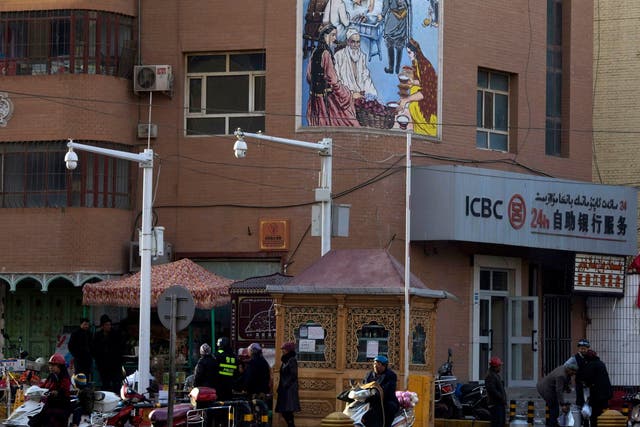 People pass by a security checkpoint and surveillance cameras on a street in Kashgar in China's Xinjiang region