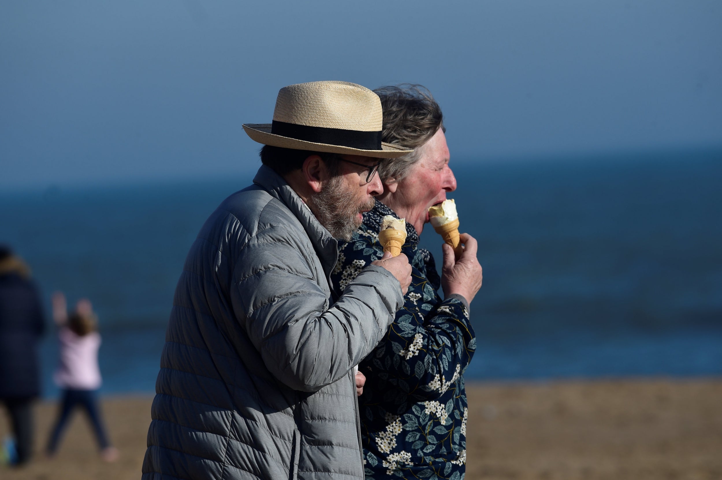 A couple eats ice cream on a beach in Pembrokeshire, Wales